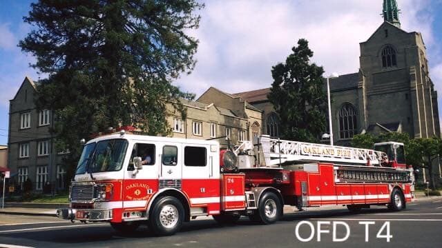 Oakland Fire Department T4 American LaFrance ladder truck in street-side profile.
